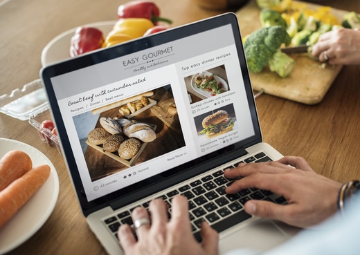 Caucasian man using a laptop in the kitchen searching for recipes